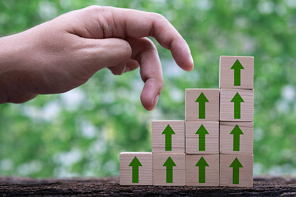 istock A hand reaches towards stacked blocks with green arrows, symbolizing growth and progress against a natural backdrop. 2232519350
