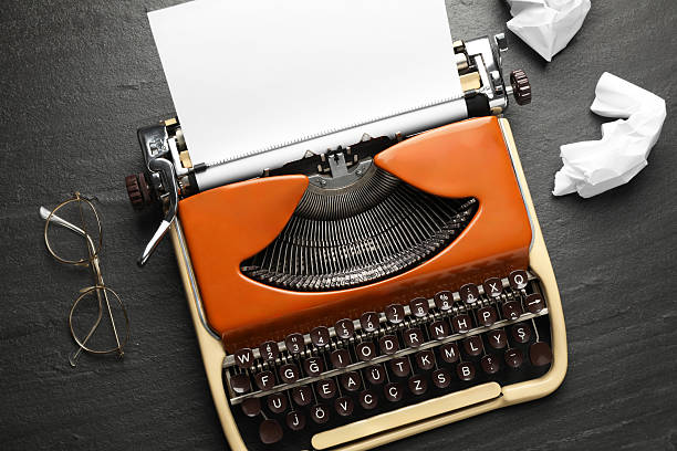 Vintage typewriter with sheet and crumpled paper on black background, top view