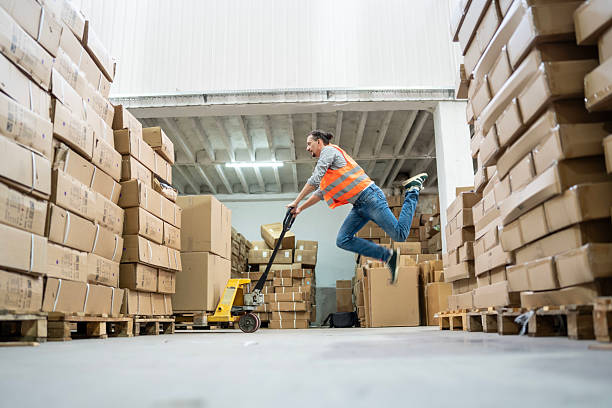 istock Warehouse Worker Balancing on Hand Truck in Active Motion 2232527959
