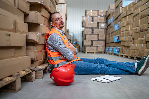 istock Tired Warehouse Worker Resting Among Stacked Boxes in Industrial Storage Facility 2232528187