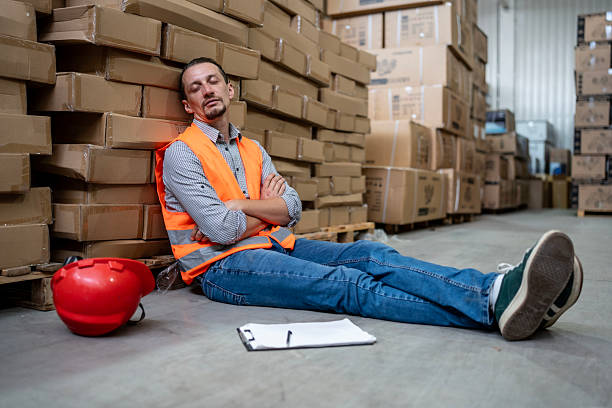 istock Warehouse Worker Resting in Safety Gear Among Cardboard Boxes 2232528194