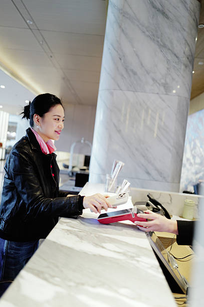 istock Woman Pays at Hotel Reception Desk - Gracious & Modern 2232530297