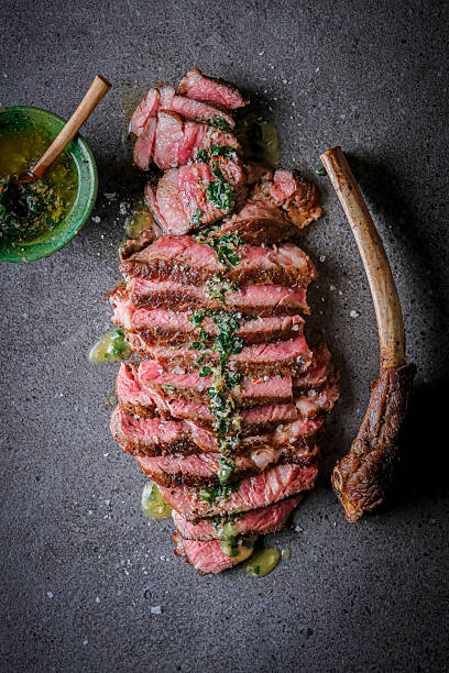 istock Grilled Tomahawk Steak with Herb Salsa Served on Stone Plate with Sauce 2232530685