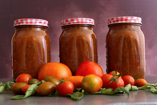 istock Jars of Tomato Sauce with Fresh Tomatoes and Basil on a Rustic Background 2232530712