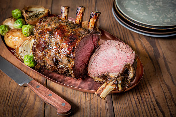 istock Succulent Prime Rib Roast Served With Vegetables on a Rustic Dining Table 2232530950