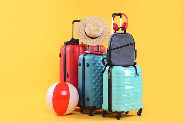 istock Travel abroad. Packed suitcases, backpack, beach ball and hat on yellow background 2232531929