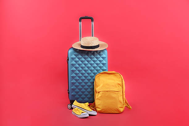istock Travel abroad. Suitcase, backpack, hat and shoes on red background 2232531930