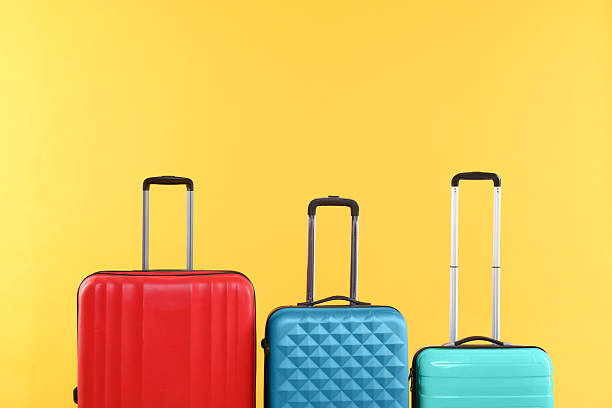 istock Different packed suitcases on yellow background, space for text. Travel luggage 2232532001