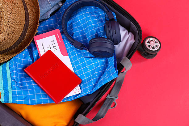 istock Travel abroad. Packed suitcase with passport and ticket on red background, closeup 2232532011