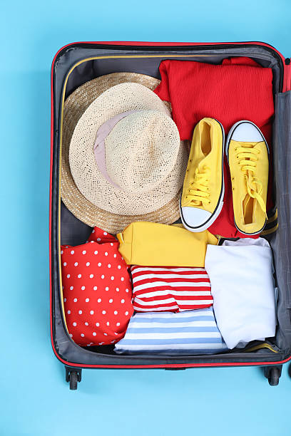 istock Travel abroad. Packed suitcase on light blue background, top view 2232532030