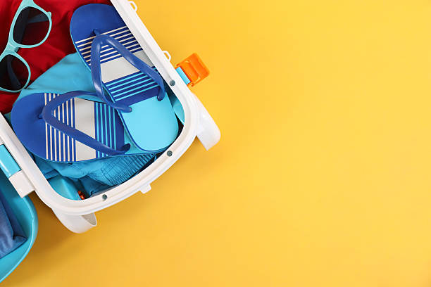 istock Travel abroad. Packed mini suitcase on yellow background, top view. Space for text 2232532090