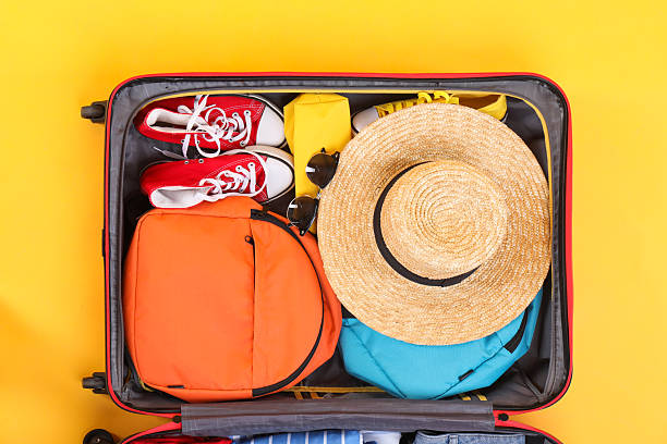 istock Travel abroad. Packed suitcase on yellow background, top view 2232532204