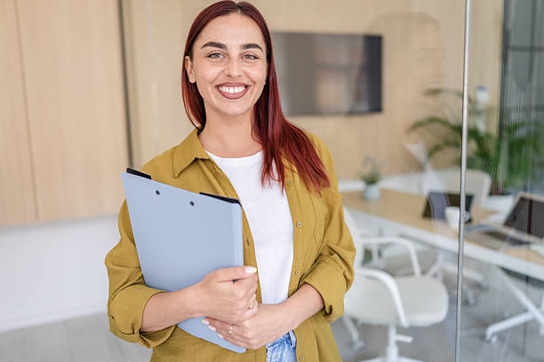 istock Bright young woman smiling while holding a folder in a modern office environment during a productive day 2232532882