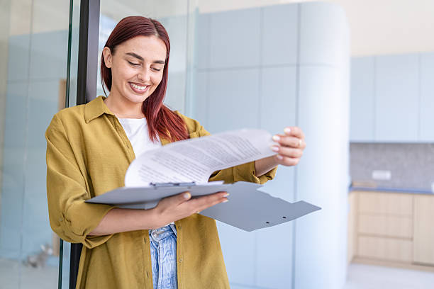 istock Young woman smiles while reviewing important documents in a modern office space during the daytime 2232537522