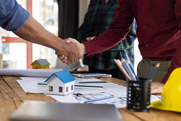 istock Architect holding blueprints is shaking hands with a client in his office during a meeting about a real estate project. 2232538137