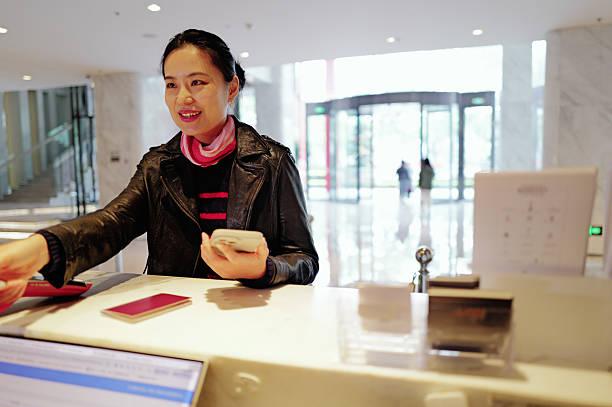 istock Woman Pays at Hotel Reception Desk - Gracious & Modern 2232538241