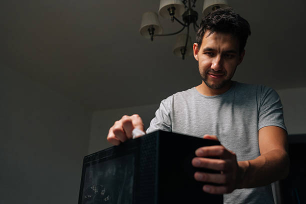 istock Low-angle view of technician male wiping computer case, removing dust and grime for maintaining electronic device cleanliness and functionality. 2232538312