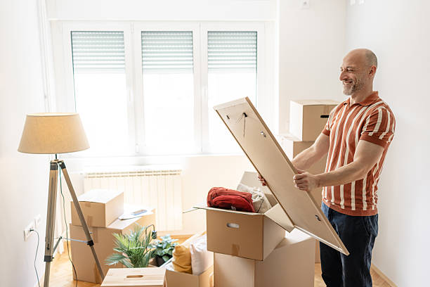 istock Happy man unpacking in his new home with moving boxes around him 2232538535