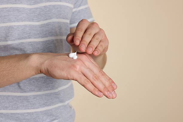 istock Man applying hand cream on beige background, closeup. Space for text 2232539676