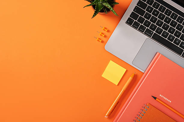 istock Laptop keyboard with orange stationery, notebook, pen, and sticky note on desk. Workplace with copyspace. 2232541322