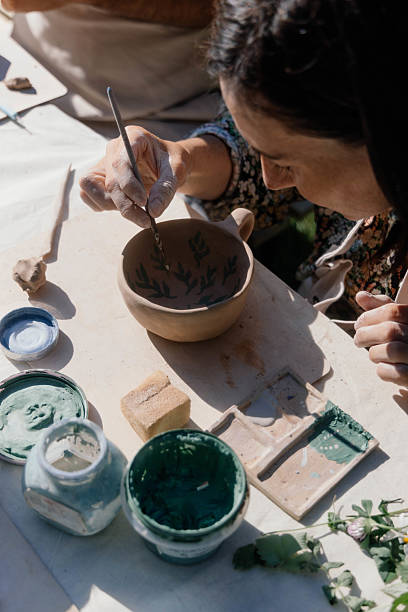 istock A person carefully paints delicate patterns on a clay cup at a pottery workshop held outdoors, surrounded by various tools and materials for ceramics 2232542819