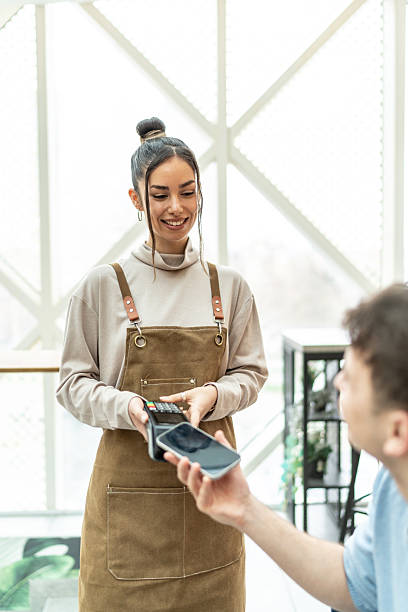 istock Smiling cashier accepting contactless payment from customer 2232543668
