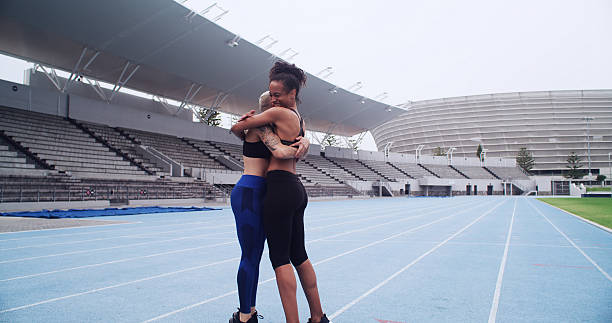 Exercise, women and celebration with hug in stadium for workout, marathon race or running. Athlete friends, smile and outdoor challenge for fitness goals, teamwork or support for cardio achievement