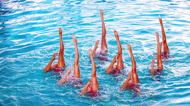 istock Group of athletes performing synchronized swimming routine in clear blue pool water during bright daylight 2232548282