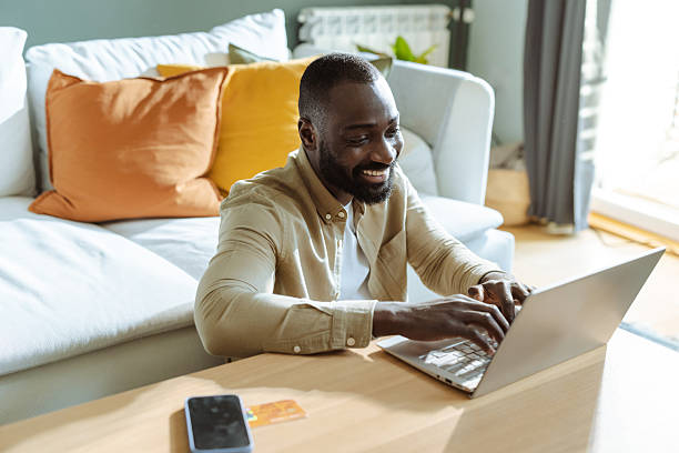 istock Man smiling while using a laptop in a cozy living room 2232551814