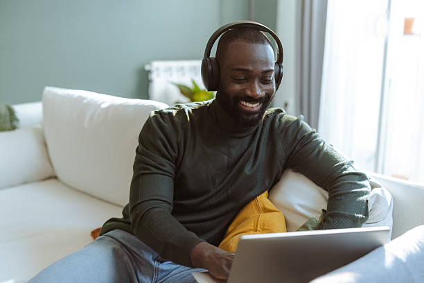 istock A man with headphones is using his laptop while relaxing on a white sofa 2232551856