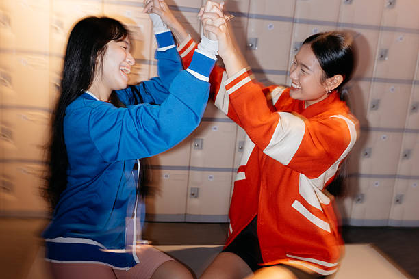 istock Two Young Women Laughing and Holding Hands Indoors 2232556933