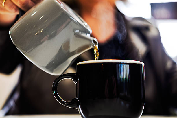 istock Pouring hot coffee into a black mug. 2232558264