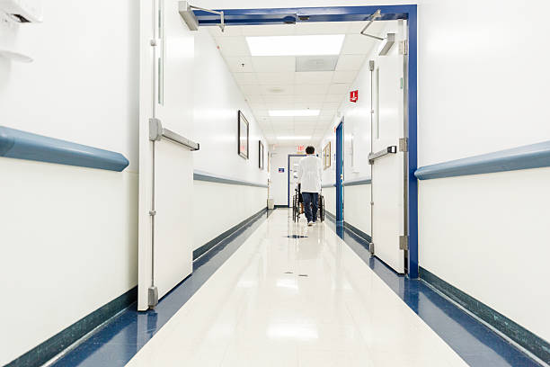 Healthcare worker assisting patient in wheelchair. Hospital hallway.