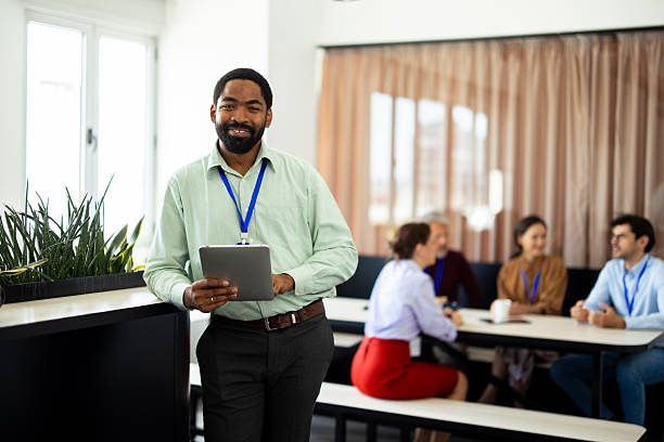 istock Smiling businessman using digital tablet with coworkers at the background 2232561111