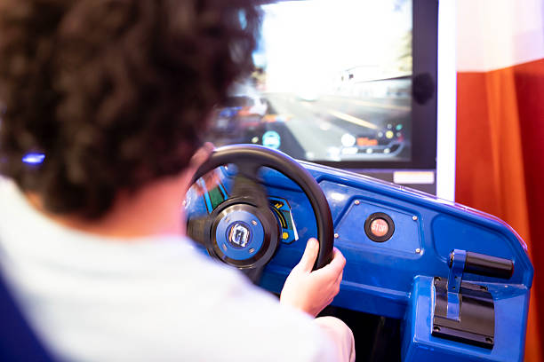 A person engages with an immersive video racing game in a vibrant arcade setting, steering creatively.