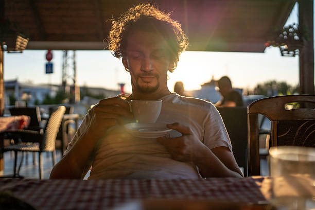 Man Enjoying Coffee at a Sunset-Lit Cafe Locale