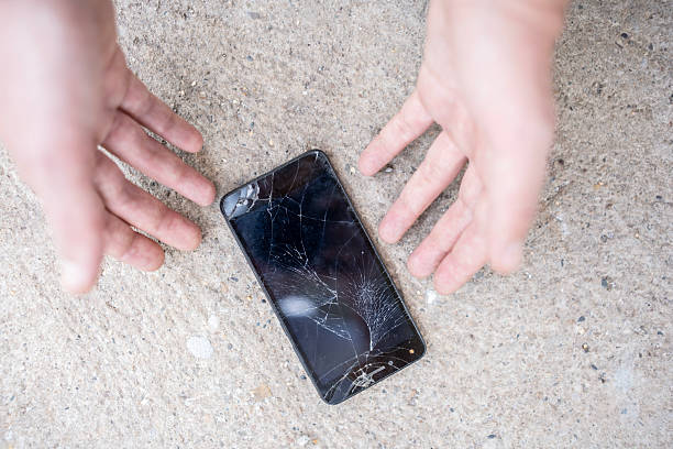istock Cracked Smartphone on Pavement with Hands Hovering Nearby in Concern 2232565540