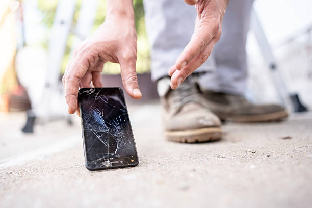 istock Close-Up of a Broken Smartphone on Pavement Being Picked Up 2232565541
