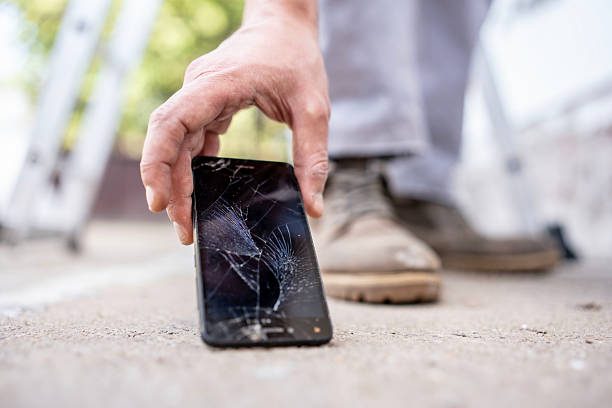 istock Closeup of Hand Picking Up a Smartphone with a Cracked Screen 2232565552