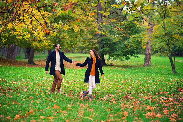 Happy young couple having fun in the forest on a beautiful autumn day.