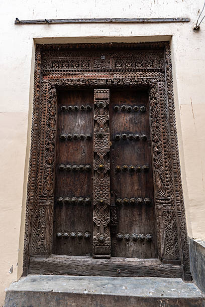 An intricately carved Swahili wooden door in Stone Town, Zanzibar, showcasing detailed floral and geometric patterns.