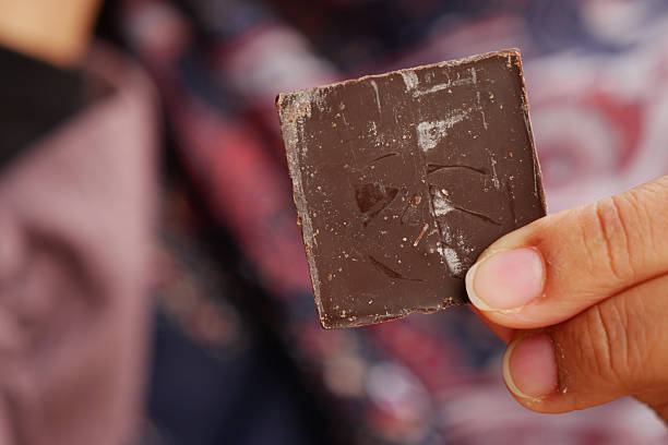 istock Hand holding a piece of dark chocolate in a vibrant setting 2232581019