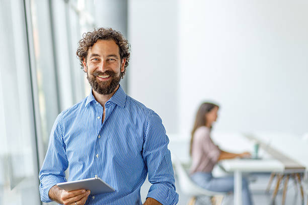 istock Smiling businessman holding digital tablet in modern office 2232581435