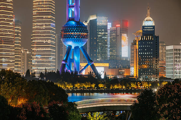 Shanghai, China-November 4, 2014 : Man in white uniform practicing Taichi at Bund, Shanghai facing city skyline in the evening, there are many tourists at the famous place.