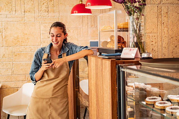istock Young waitress using mobile phone at coffee shop 2232588658
