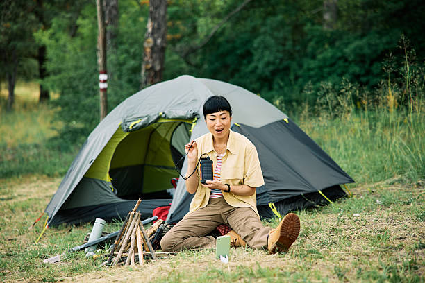 istock Camper Demonstrates Camping Gear Next to Tent in Forest Setting 2232592858