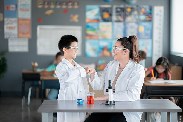 A teacher assists a student conducting a science experiment in a vibrant classroom setting, promoting interactive STEM education and fostering curiosity.