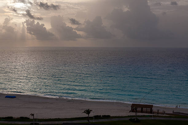 Gentle morning sun rays breaking through clouds over the calm Caribbean waters, Cancun, Mexico.