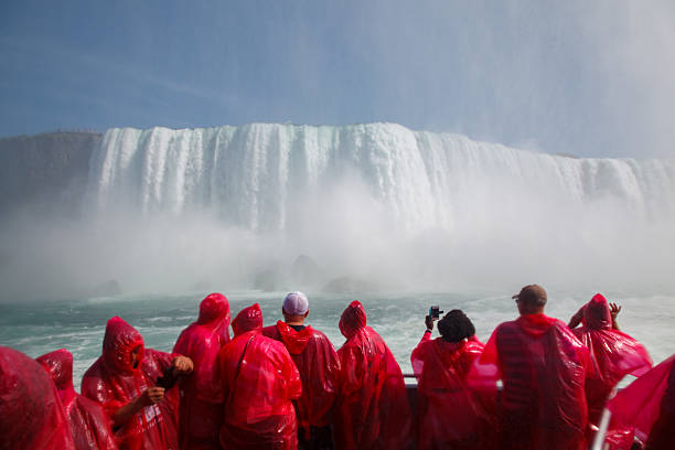 Group of wet Tourists looking the Impressive Horsehoe Falls, Niagara river, Niagara Falls, Ontario, Canada