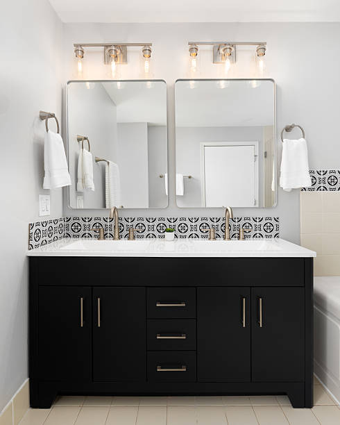 istock A bathroom with a black cabinet, bronze fixtures, and a tiled backsplash. 2232609862